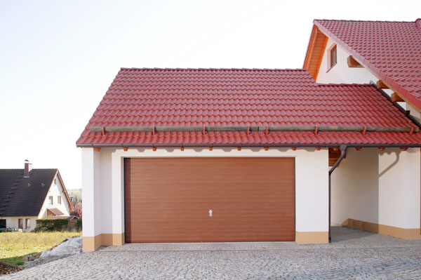 Haus mit rotem Dach und Garagentor mit Holzverkleidung